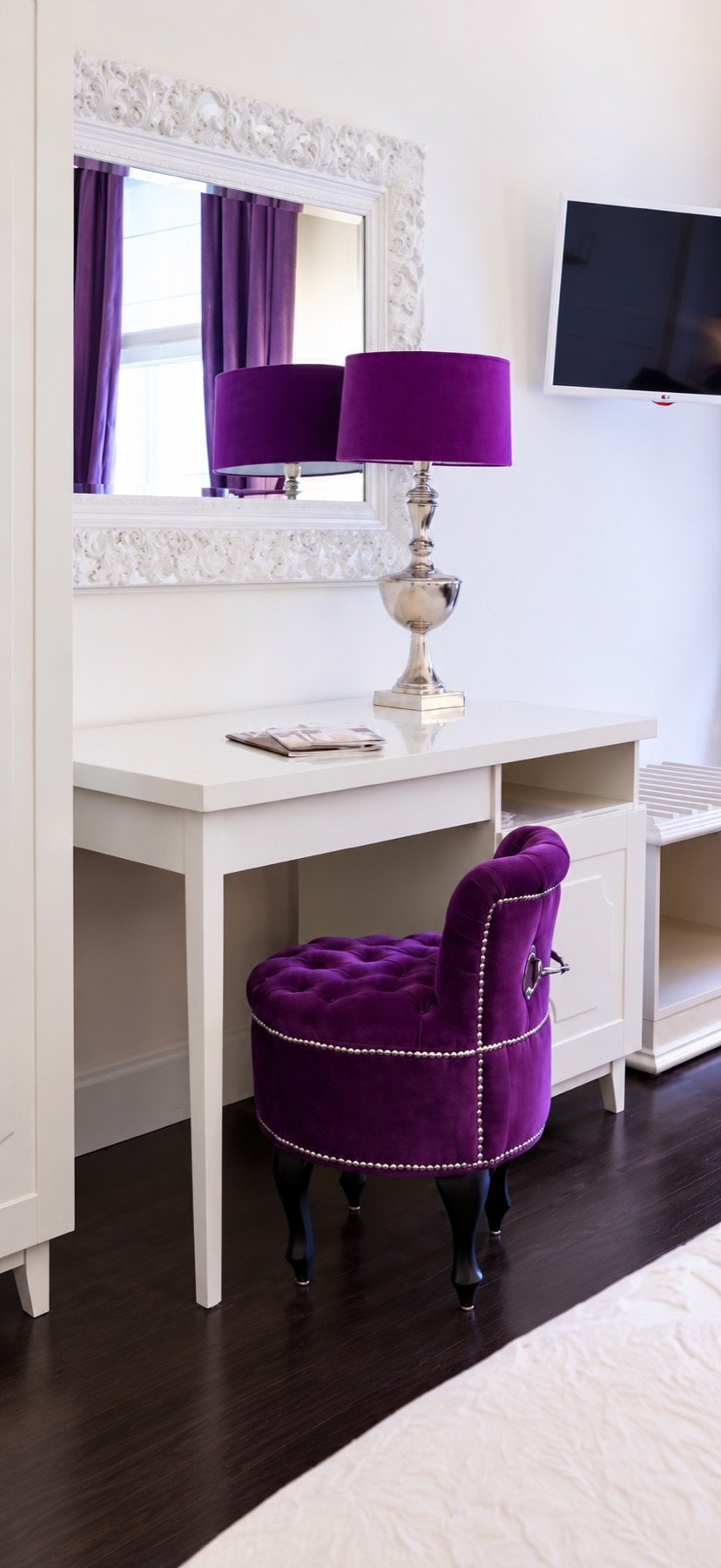 A purple velvet chair and lamp beside an ornate mirror