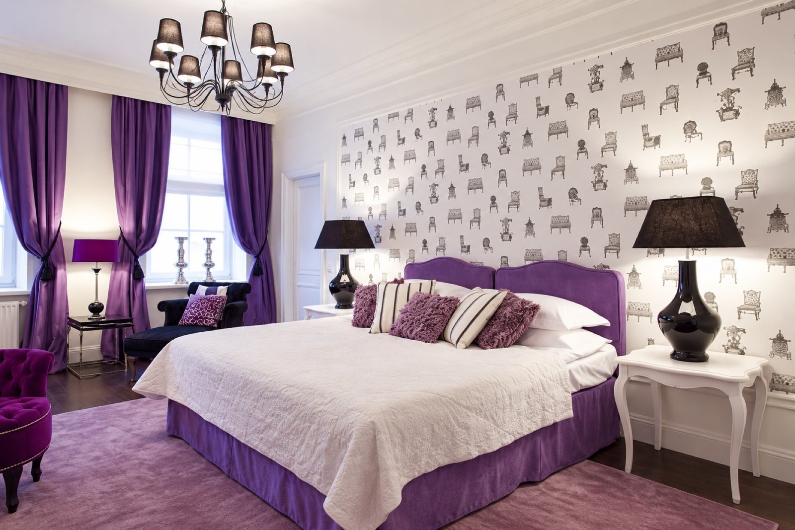 A purple-accented APIA bedroom with a chandelier and patterned wallpaper