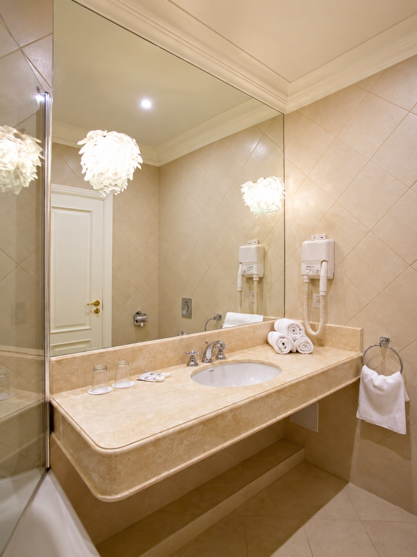 A cream-toned private bathroom with a broad mirror